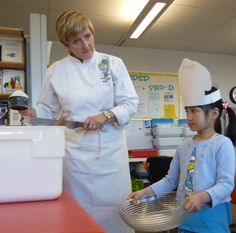 Master Chef Barb shows the proper way to measure flour with the help of Chef Tiffany. Photo by Julie Cheng